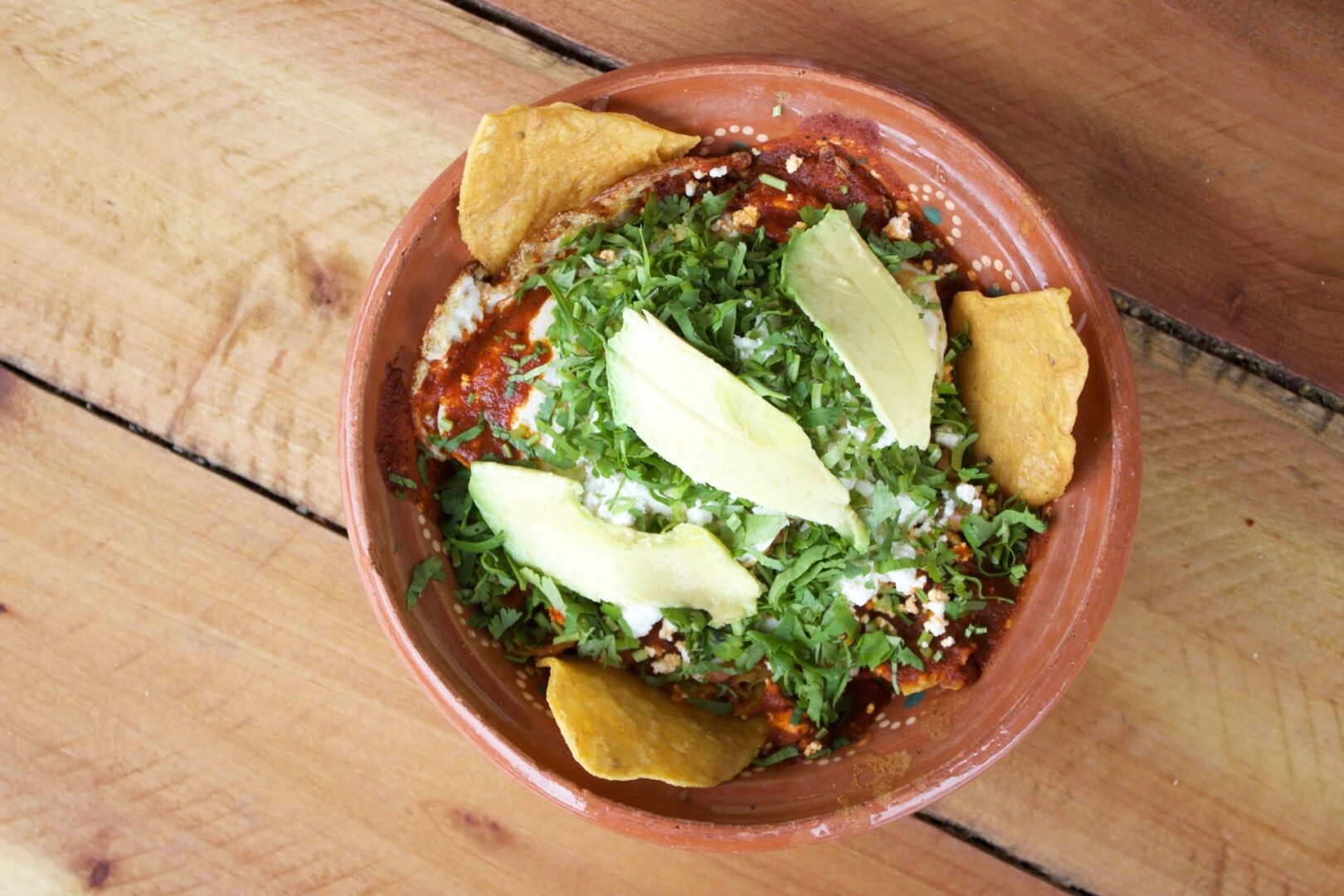 A bowl of nachos Kept on a wooden table